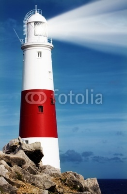 Lighthouse on rocks with lightbeam on Portland