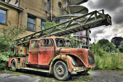 Vintage abandoned firetruck in front of a derelict building